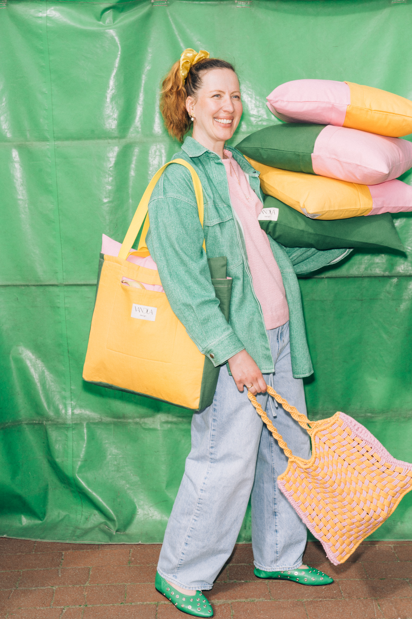 Melanie Nuhtrop mit Kissenstapel in grün,gelb, pink und Tasche von vandla