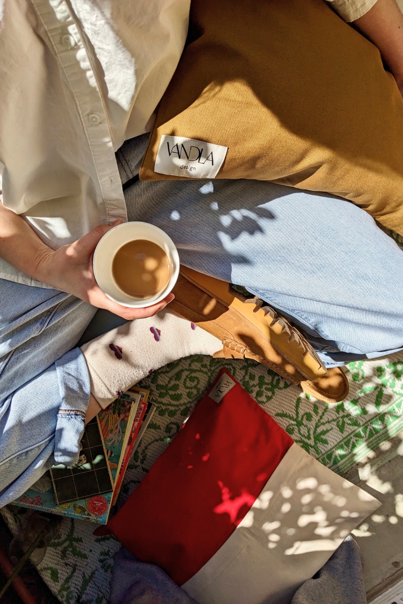 Kaffeepause im Sonnenschein auf dem Balkon mit Vandla Kissen in crem-rot und zigarre